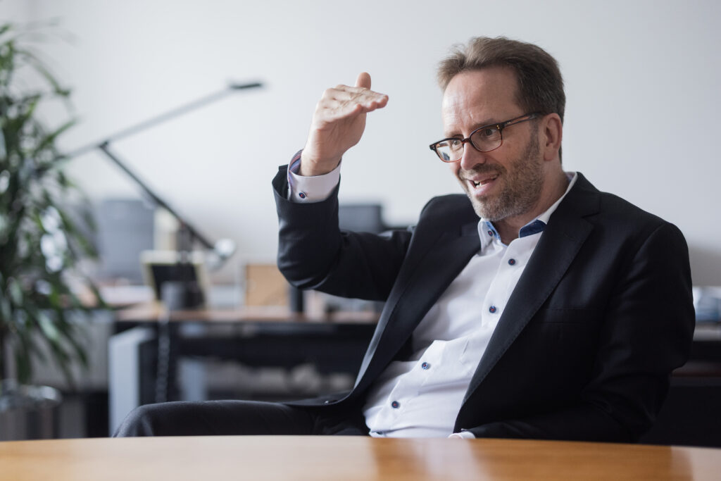 Klaus Müller hebt gestikulierend die Hand im Gespräch